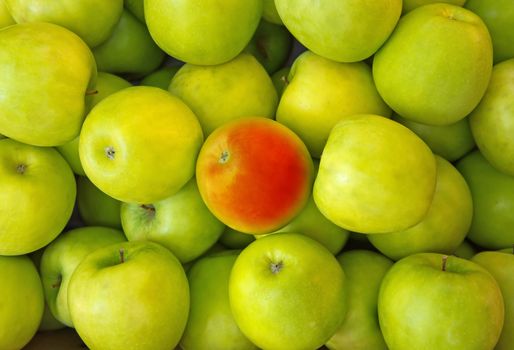 Red apple in center of green apples