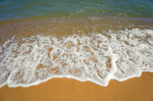 Water waves on the golden beach in sunny day