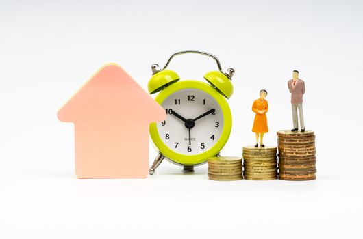 Kuala Lumpur, Malaysia - March 2, 2019 : Alarm Clock and Miniature people standing on stacking coins with white background. Business and Lifestyle concepts.