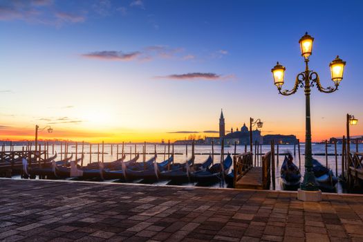 Venice with famous gondolas at sunrise, Italy. Gondolas in lagoon of Venice on sunrise, Italy. Venice with gondolas on Grand Canal against San Giorgio Maggiore church.