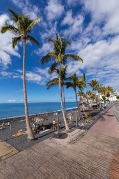 Puerto Naos beach an sunbathing people at beach with black lava sand at La Palma, Canary Island, Spain.