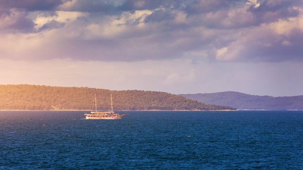 Sailboat in the sea in the evening sunlight with mountains background, luxury summer adventure, active vacation in Mediterranean sea, Croatia. Sailing ship luxury yacht with white sails in the Sea. 