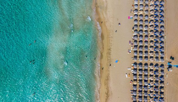 Top down aerial view of amazing beach with umbrellas and turquoise sea at sunset. Mediterranean sea, Crete, Greece.