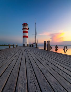 Lighthouse at Lake Neusiedl, Podersdorf am See, Burgenland, Austria. Lighthouse at sunset in Austria. Wooden pier with lighthouse in Podersdorf on lake Neusiedl in Austria.