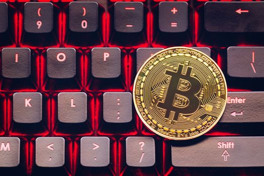 Bitcoin on compuer keyboard in background, symbol of electronic virtual money and mining cryptocurrency concept. Coin crypto currency bitcoin lies on the keyboard. Bitcoin on keyboard.