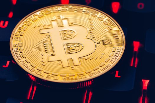 Bitcoin on compuer keyboard in background, symbol of electronic virtual money and mining cryptocurrency concept. Coin crypto currency bitcoin lies on the keyboard. Bitcoin on keyboard.
