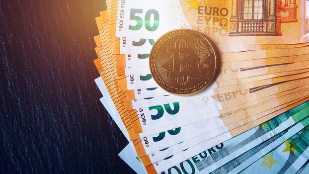 Golden bitcoin over Euro money. Bitcoin cryptocurrency. Crypto currency concept. Bitcoin with euro bills. Bitcoins stacked on euro banknotes.