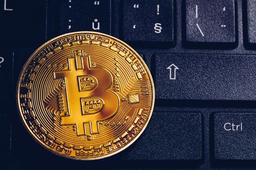 Bitcoin on compuer keyboard in background, symbol of electronic virtual money and mining cryptocurrency concept. Coin crypto currency bitcoin lies on the keyboard. Bitcoin on keyboard.