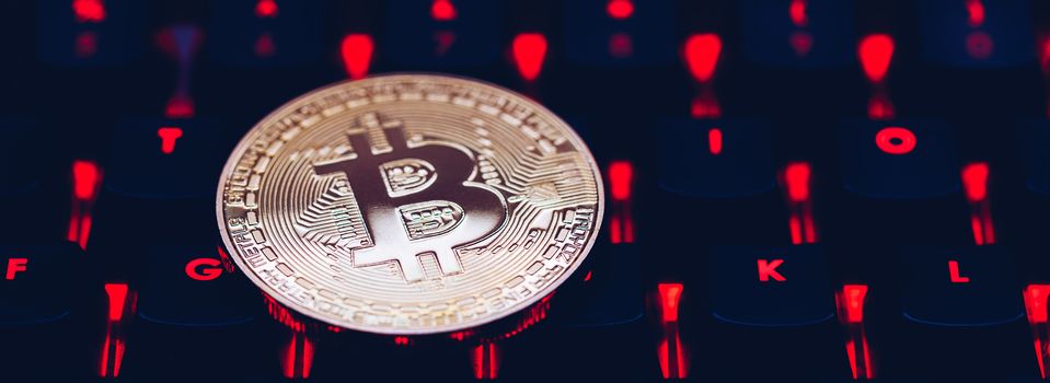 Bitcoin on compuer keyboard in background, symbol of electronic virtual money and mining cryptocurrency concept. Coin crypto currency bitcoin lies on the keyboard. Bitcoin on keyboard.