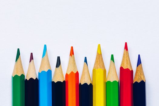 Color pencils isolated on white background. Close up of colored rainbow pencils for drawing, concept of preparing for school and discounts on stationery before the school year.