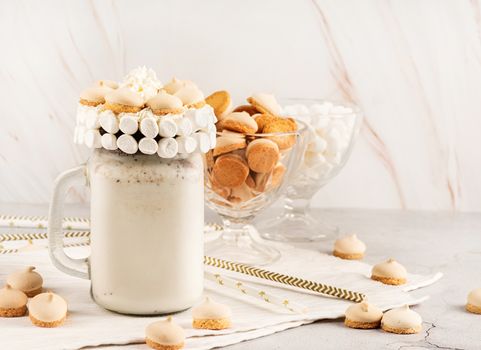 Cold chocolate milkshake in a mason jar decorated with marshamallows and cookies with copy space