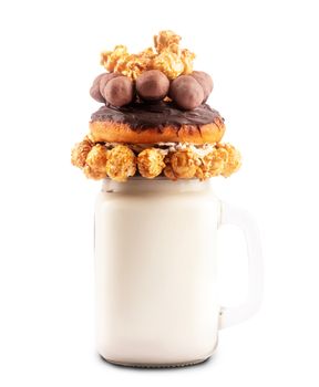 Freakshake. Extreme milkshake with donut, caramel popcorn and chocolate candies isolated on white background with clipping path