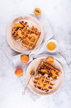 Homemade belgian waffles with apricots anf honey top view flat lay