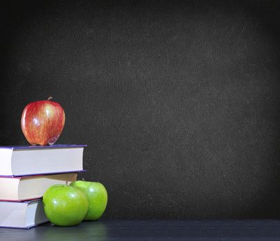 Green and red apples with books on black background.