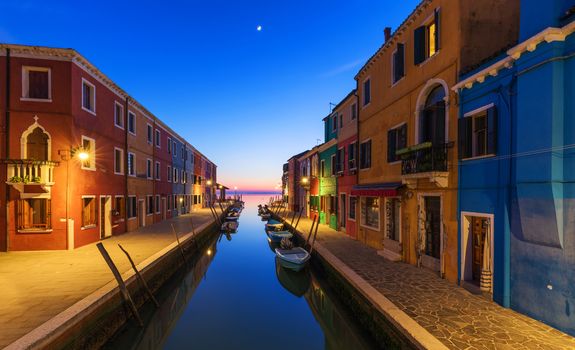 Street view with colorful buildings in Burano island at night, Venice, Italy. Architecture and landmarks of Burano, Venice postcard. Scenic canal and colorful architecture in Burano island near Venice, Italy