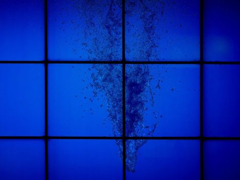 blue water flow splash behind glass wall useful as a background