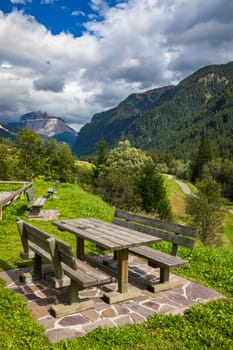 Nature landscape. Amazing view on Alps, valley and mountains at summer. It's time for lunch in the mountains. Picnic table in Dolomites mountains, wooden bench in the mountain valley.