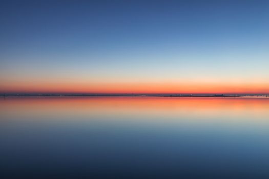 Mirroring sky in the water at twilight. Summer night picture of the surface of a calm lake mirroring the sky