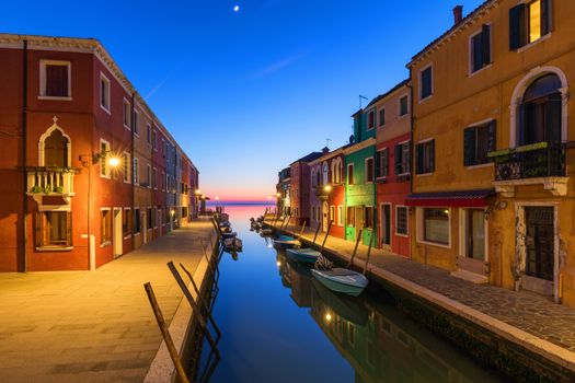 Street view with colorful buildings in Burano island at night, Venice, Italy. Architecture and landmarks of Burano, Venice postcard. Scenic canal and colorful architecture in Burano island near Venice, Italy