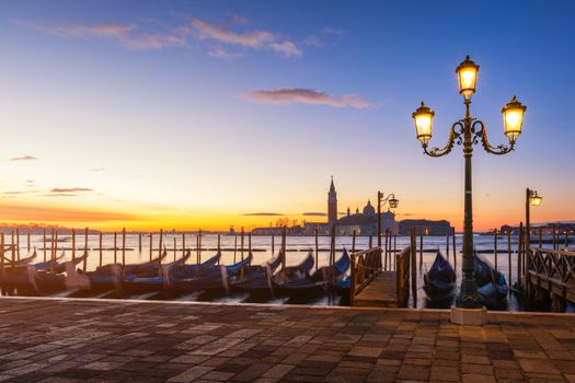 Venice with famous gondolas at sunrise, Italy. Gondolas in lagoon of Venice on sunrise, Italy. Venice with gondolas on Grand Canal against San Giorgio Maggiore church.