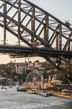 Sydney, Australia - February 12, 2019: closeup of Harbour bridge north side landing during sunset with Kirribilli neighborhood and Luna Park. Boats on water. Portrait.