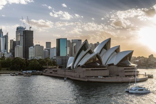 Sydney, Australia - February 12, 2019: Northeast corner view of the Opera House during sunset. Light Blue and brown sky and gray and silver water. Horizon is south shore skjyline.