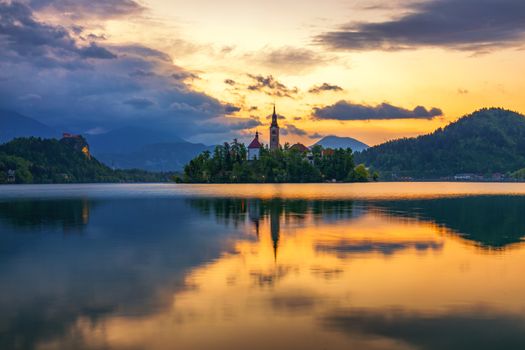 Dramatic sunrise on lake Bled, sunrise view on Bled lake, island, Pilgrimage Church of the Assumption of Maria and Castle with mountain range (Stol, Vrtaca, Begunjscica). Bled, Slovenia,