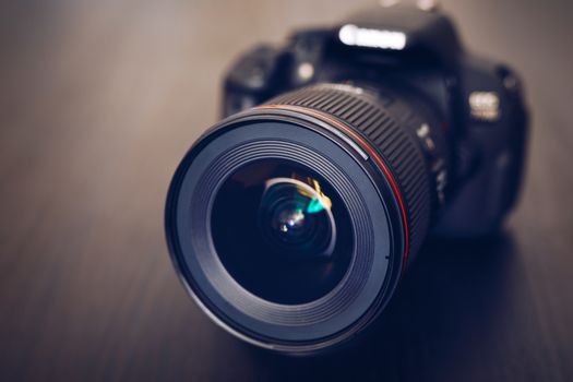 Digital camera or DSLR with camera lens with lense reflections. Photo Camera or Video lens close-up on black background DSLR objective