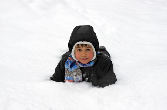 Funny little boy playing in snow, outdoors in winter