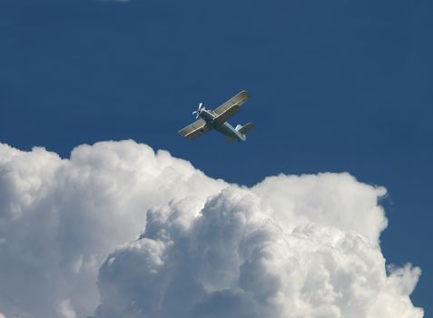 Blue sky with clouds and plane flying away. 