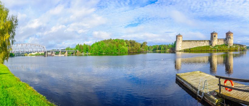 Panoramic view of a train bridge and the Olavinlinna castle in Savonlinna, Finland. It is a 15th-century three-tower castle