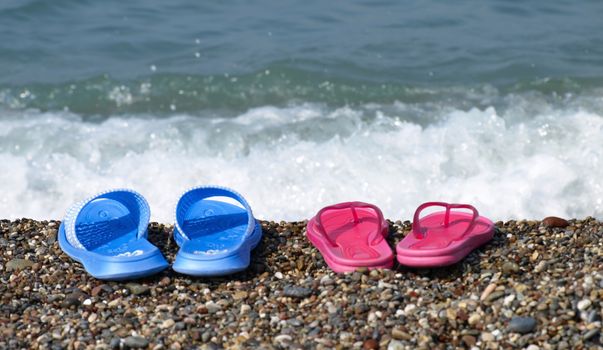 Blue and red flip-flop sandals on beach shore