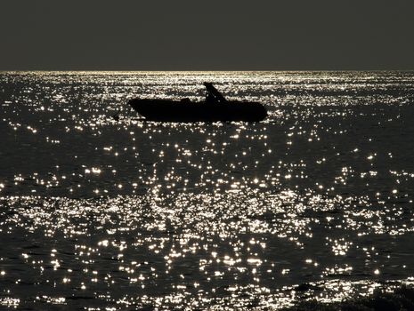 Little fishing boat on the sea at night lit by the moonlight