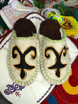 Kazakh national handicraft slippers over colored background.