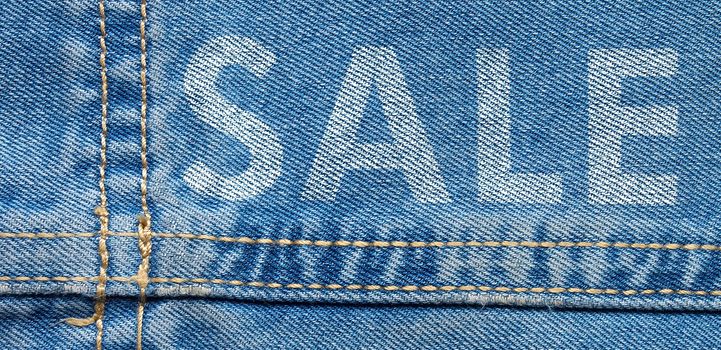 High resolution detail of denim jeans with double-stitched seam and text SALE.