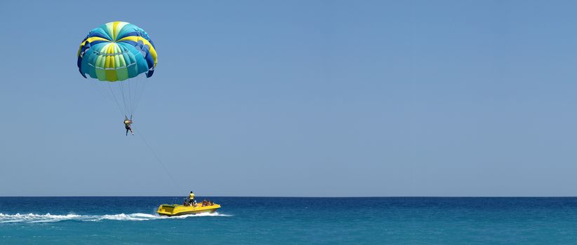 Panoramic photo. One man is parasailing over the the Mediterranean Sea.