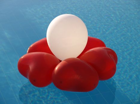 Abstract decoration of inflated heart-shaped balloons on a water.