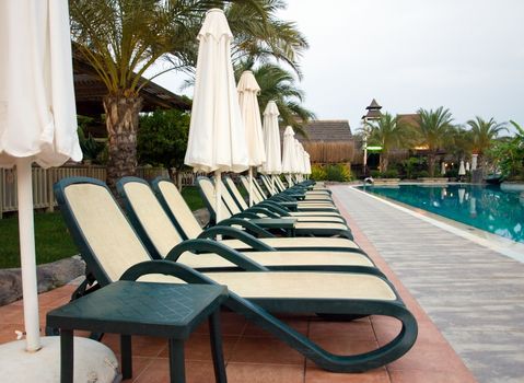 Chaise longue and umbrellas near the swimming pool. 