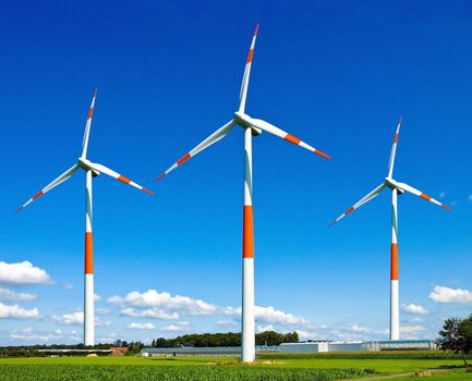 Wind turbines generating electricity on the beautiful green meadow.