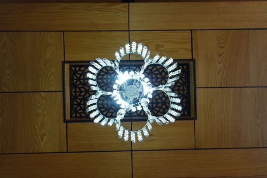 a beautiful cristal light decor on a wooden ceiling.