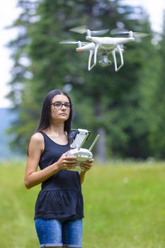 Teenage girl controlling drone with remote control and having fun in summer time.  Focus on her face.