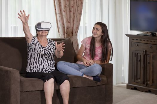 Senior woman with virtual reality headset or 3d glasses having fun with her granddaughter. People having fun with new technology concept. Focus on senior woman face.