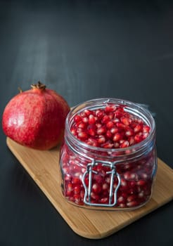 Ripe pomegranate fruit in a jar on wooden vintage background
