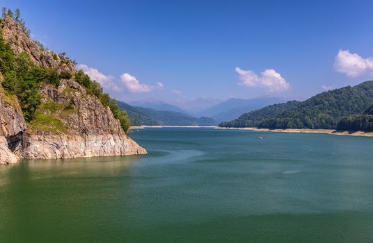 Summer scenery of Vidraru Dam and lake glowing in sunlight. Vidraru Dam, Romania. Carpathian Mountains, Fagaras ridge.