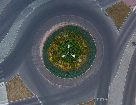 Roundabout at city streets with plants and high lamp at center