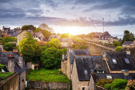 Beautiful view of scenic narrow alley with historic traditional houses and cobbled street in an old town of Dinan with blue sky and clouds. Brittany (Bretagne), France