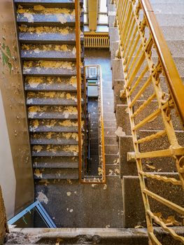 Dirty concrete staircase with metal railings in old abandoned hospital