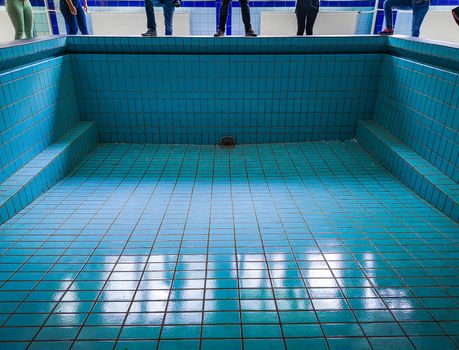 People standing on wall of empty swimming pool in old abandoned hospital