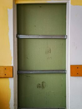 Old barred doors with footprints on inserted wall in old abandoned hospital
