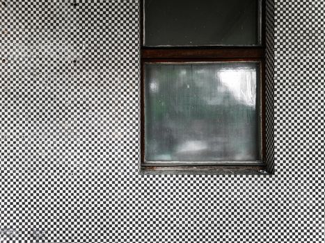 Old covered window at facade of mosaic black and white tiles